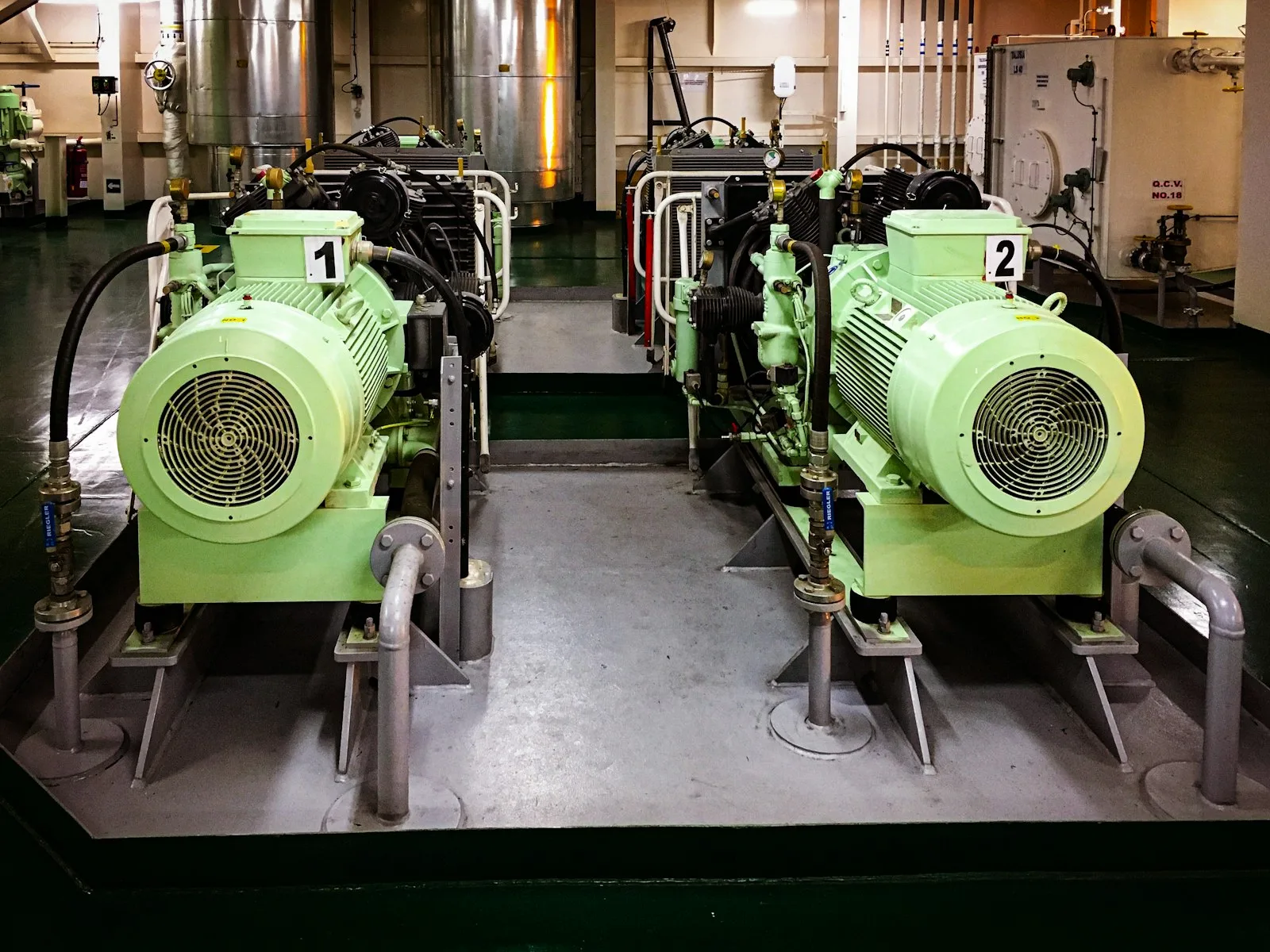 Ship engine-room pump and motor skids with bolted bases, hose connections and service piping
