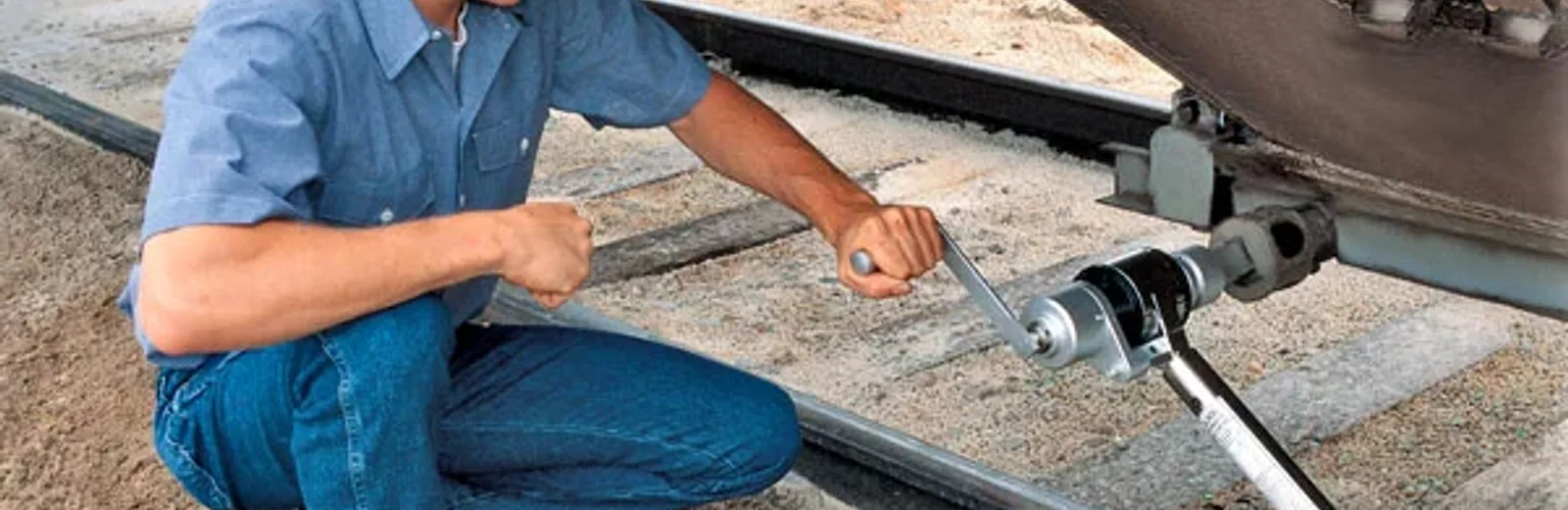 Technician using a torque tool below a railway carbody underframe